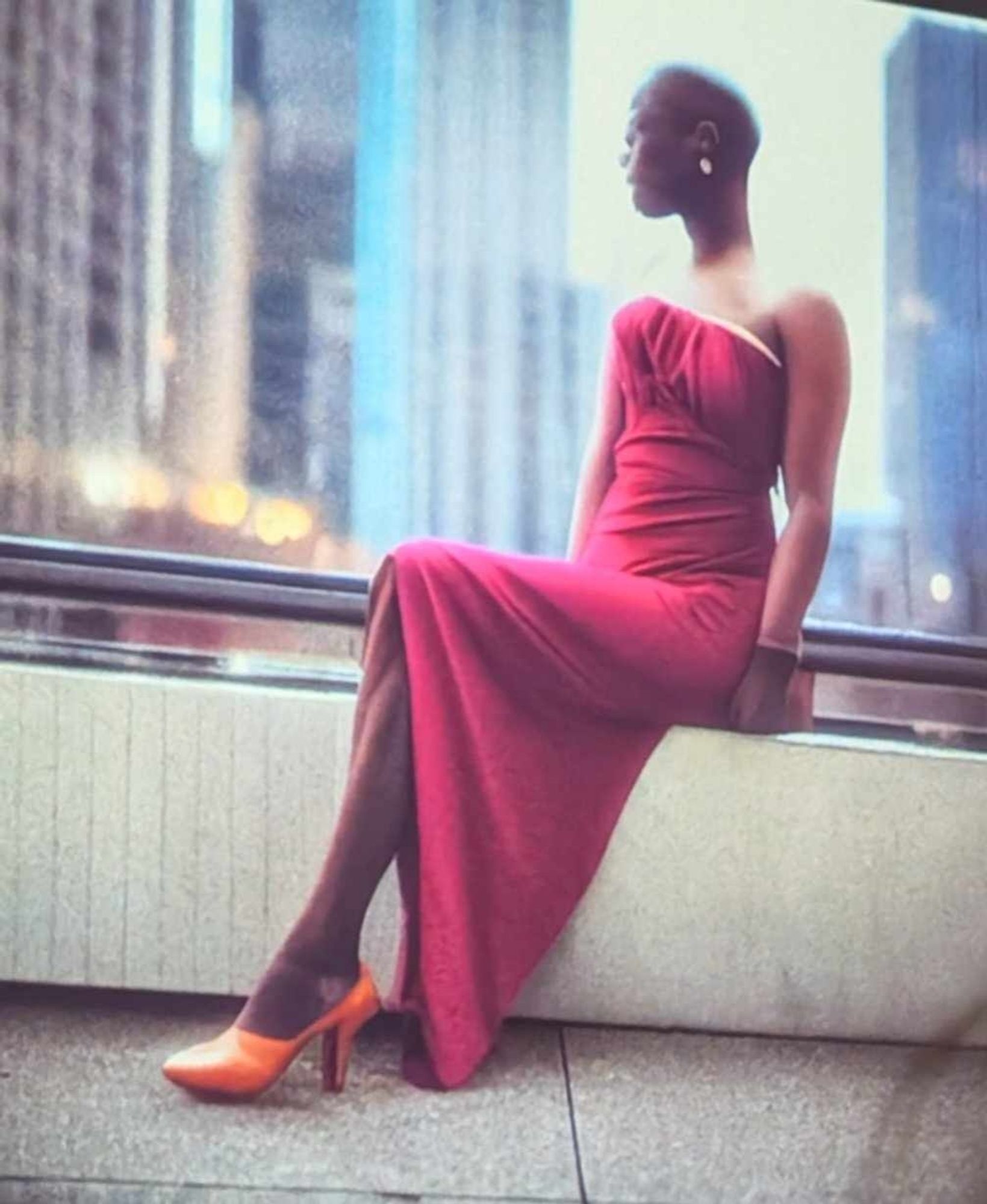 An image of a Black woman sitting on a railing. She is wearing a pink strapless dress. She is bald and her face is indistinct. Her legs seem to fuse into one single leg, wearing one single orange high heeled shoe.